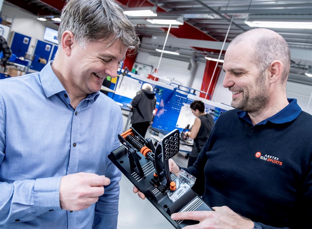 Asetek’s CEO André Eriksen og Henrik Gertz, VP Global Operations, (de to på foto 1 – André med logo på mørkeblå trøje) glæder sig - sammen med medarbejdere i den nye afdeling - over, at produktionen af de første SimSports produkter nu er godt i gang – og allerede overstrømmende bedømt af internationalt anerkendte anmeldere.
(Foto: Asetek SimSports / René Schütze)